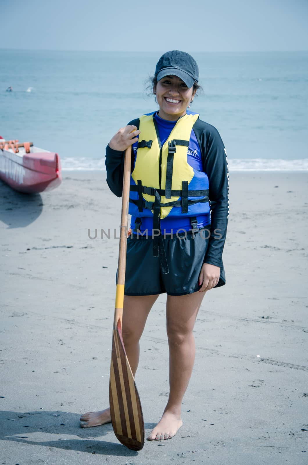 Young woman paddler smiling with an oar in hand at the seashore