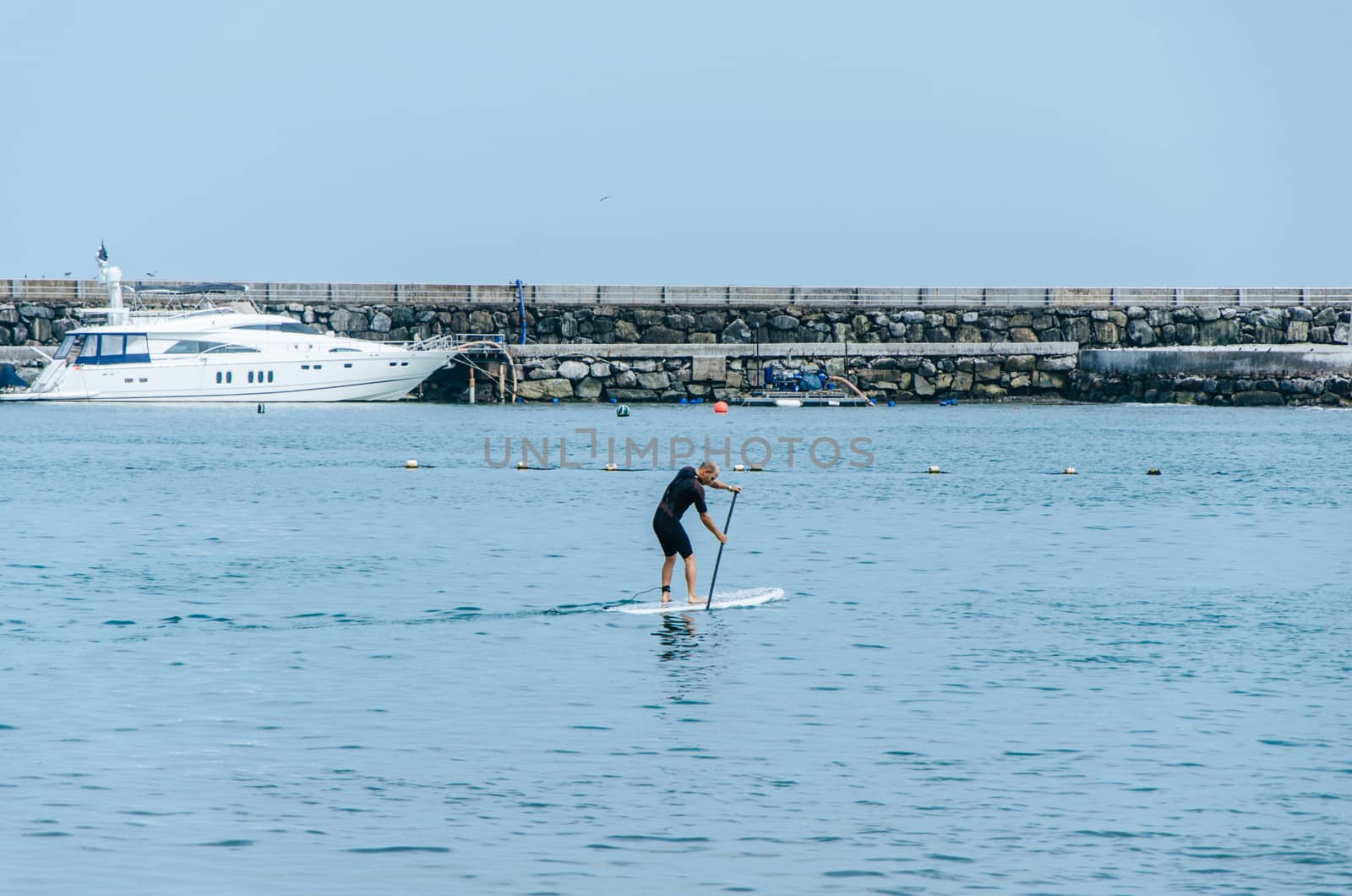 Stand up paddle board man paddleboarding on Peruvian beach standing happy on paddleboard on blue water. Summer holidays vacation travel.