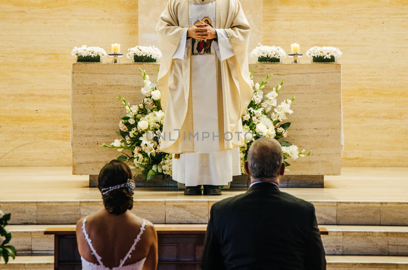 Newlyweds sitting in front of the Bride and groom sitting in front of the altar during the wedding ceremonyaltar during the wedding ceremony