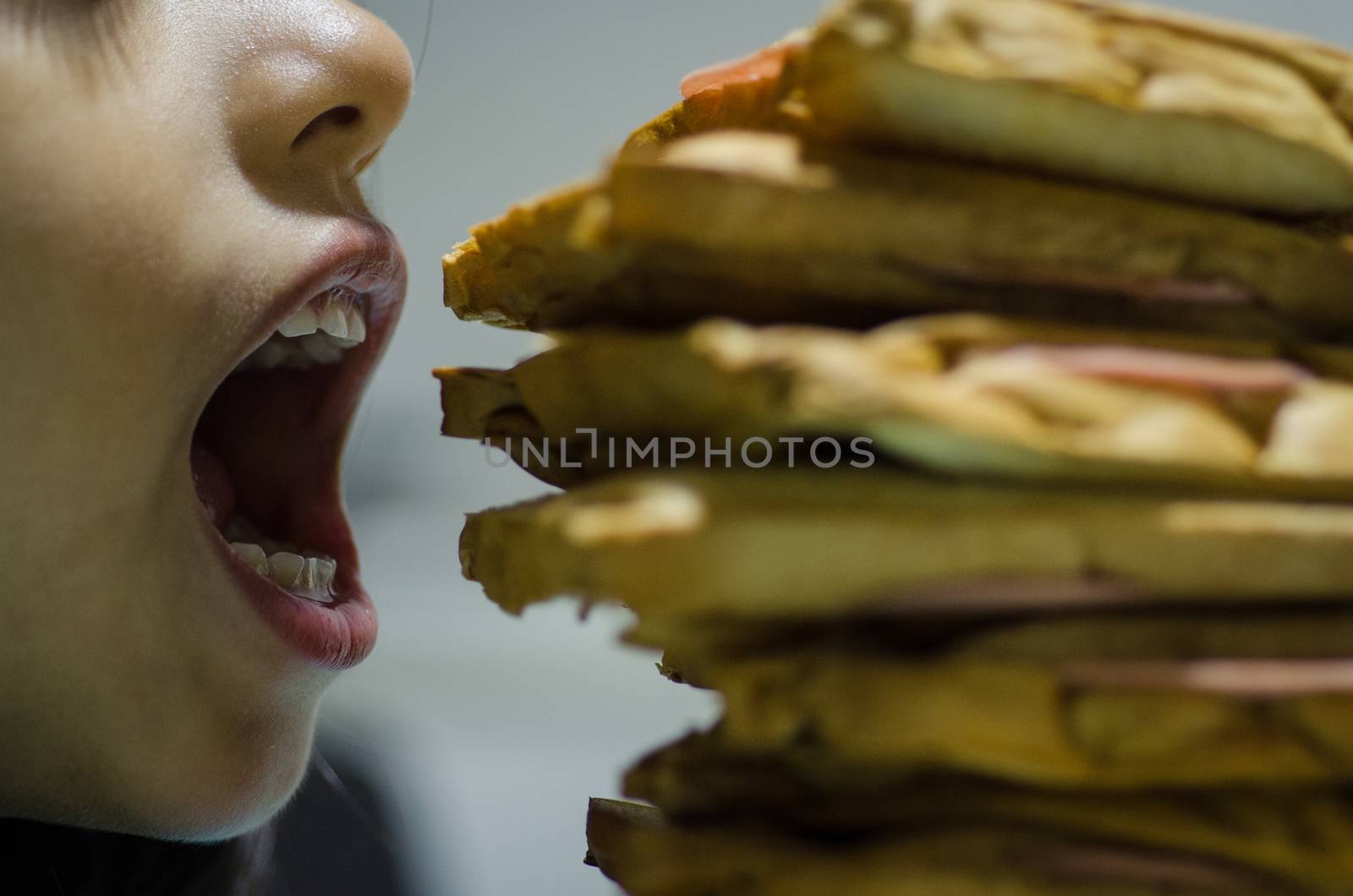 Concept of hungry girl devouring a tower of sandwiches