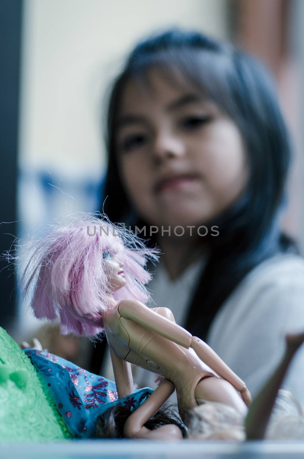 Cute little girl playing with toy doll, doll close-up with defocused girl background, concept image