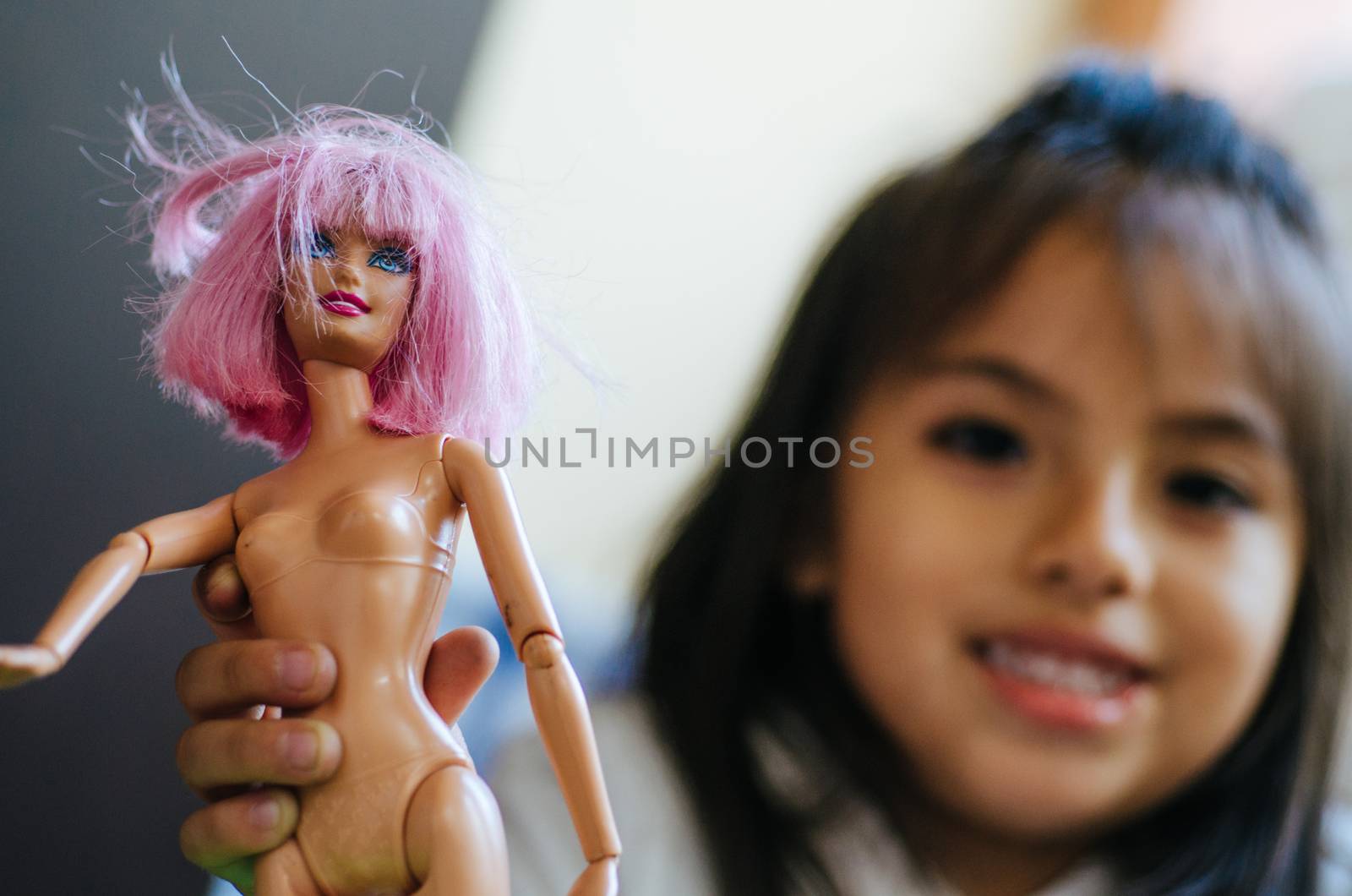 Cute little girl playing with toy doll, doll close-up with defocused girl background, concept image