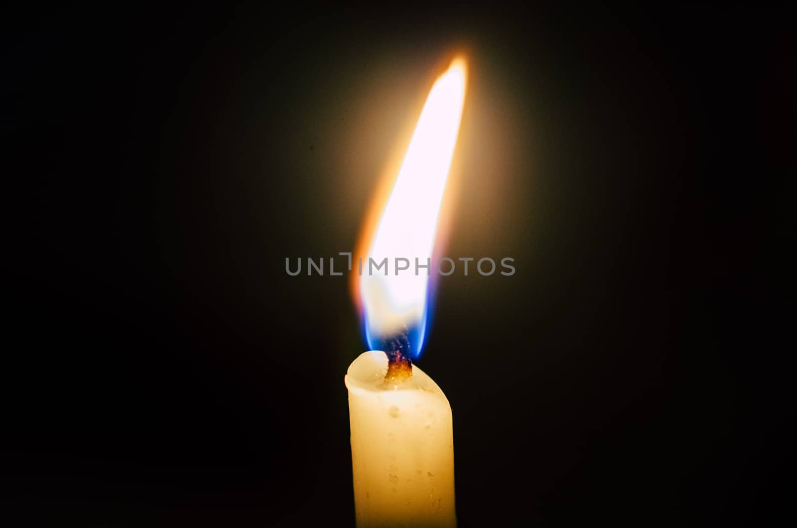Old candle melting and shining in the darkness