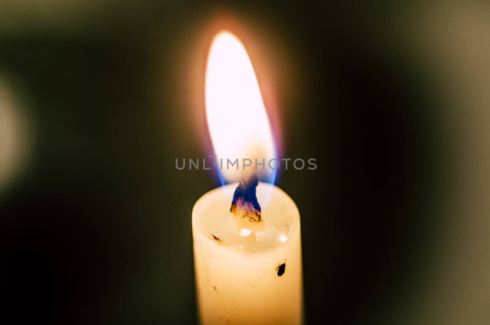 Old candle melting and shining in the darkness