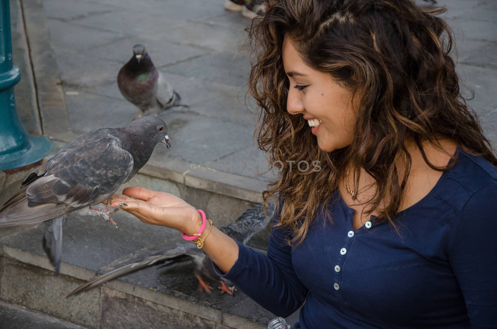 A smiling woman feeding a pigeon from her hand in the park