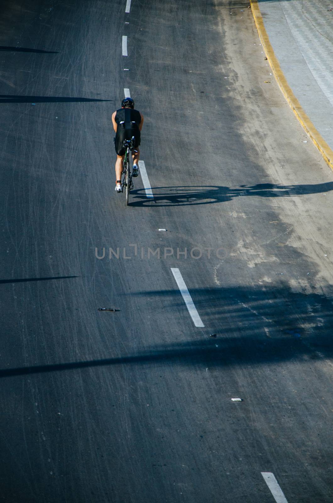 Cyclist on the road at full speed, shadow of cyclist