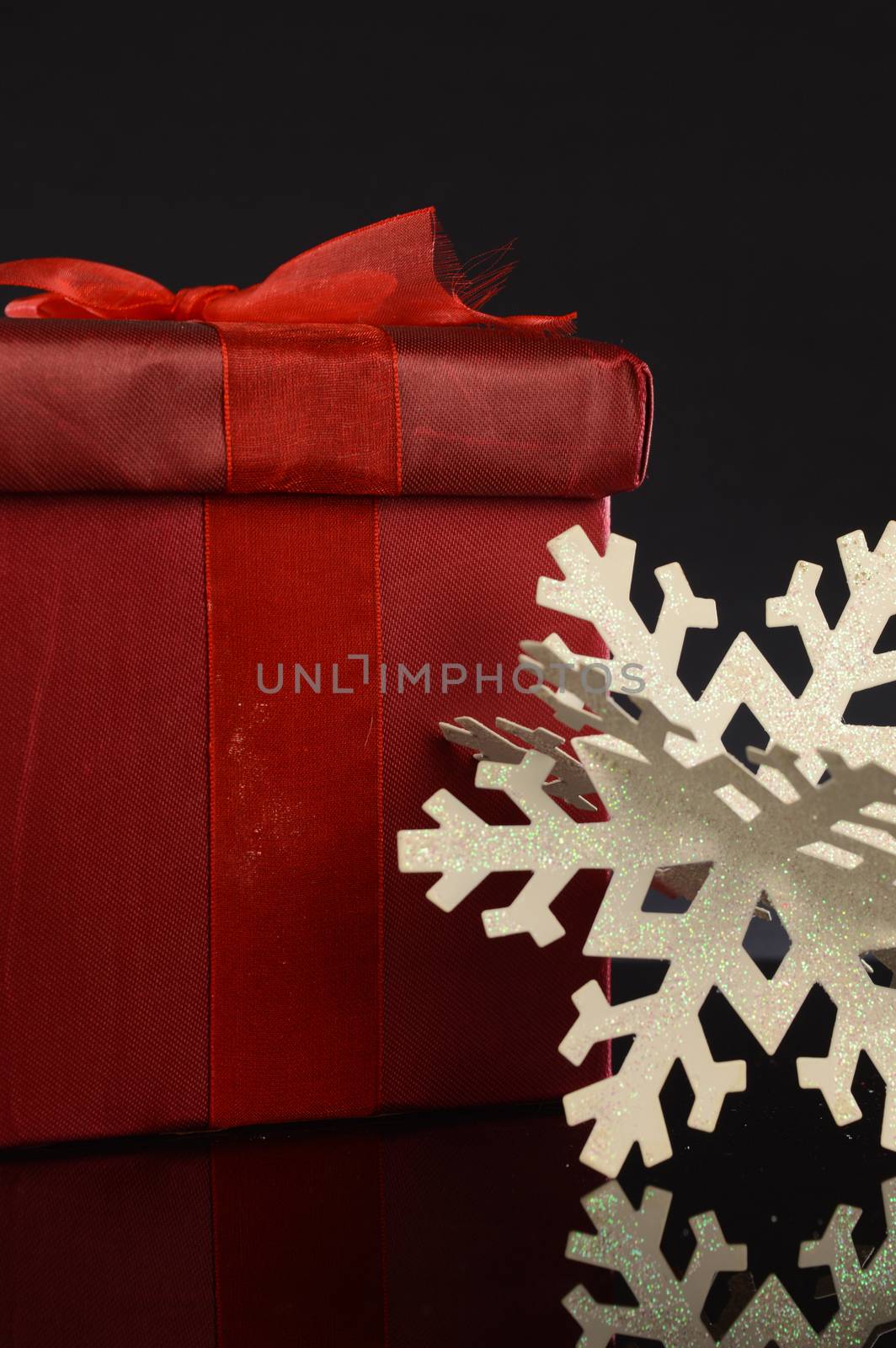 A closeup image of a red Christmas gift with decorative items to compliament the festive season.
