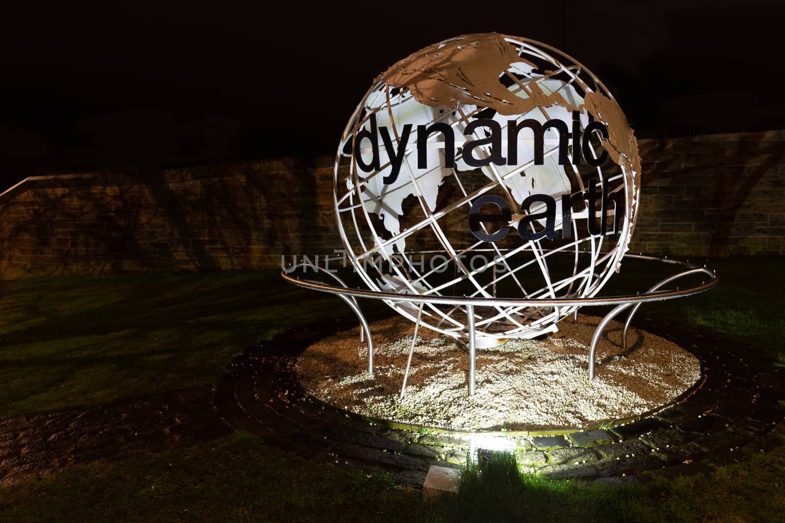 Globe at entrance of dynamic earth with black text and spotlights in Scotland