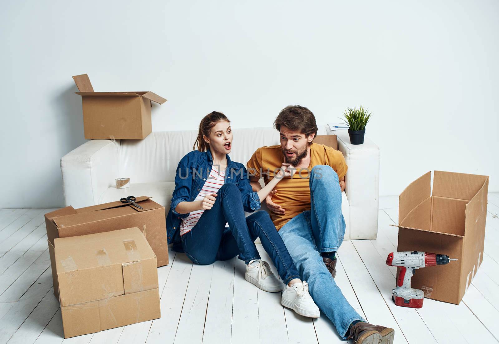 Emotional man and woman with cardboard boxes on the floor having fun moving renovation work by SHOTPRIME