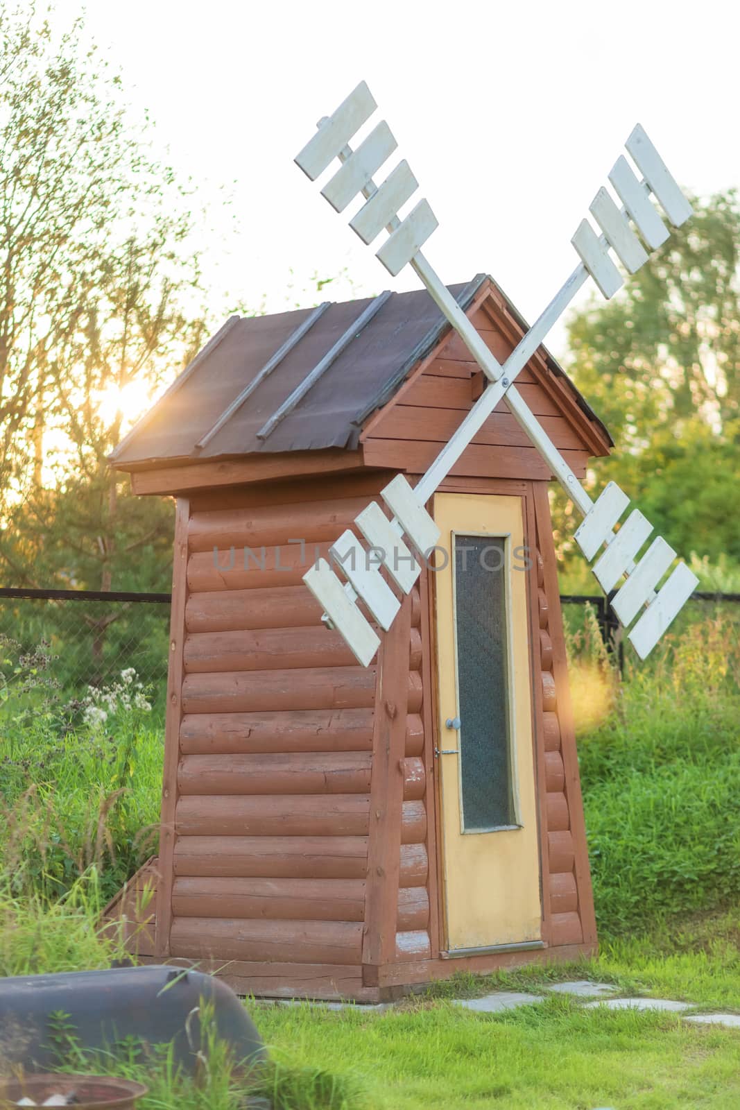 Rustic outdoor toilet in the form of a windmill.