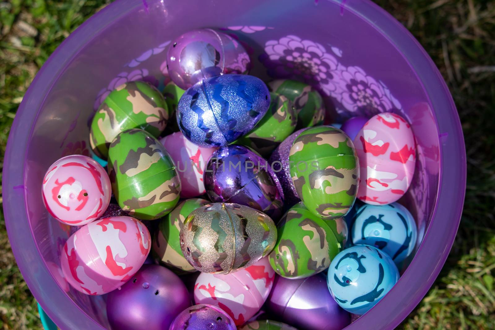 Top view of pink easter basket full of Bright eggs in green grass . High quality photo