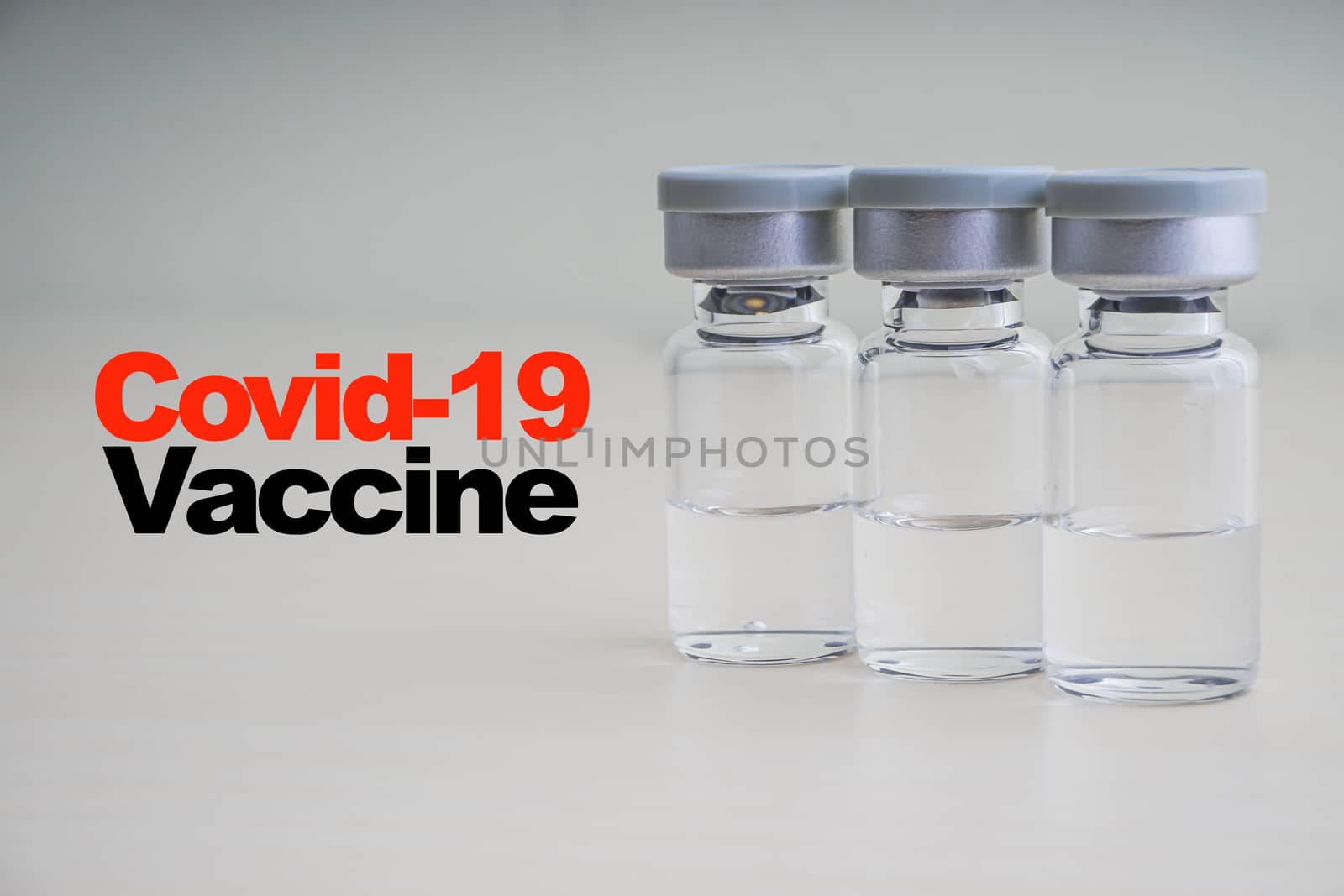 COVID -19 VACCINE text with vials on wooden background by silverwings