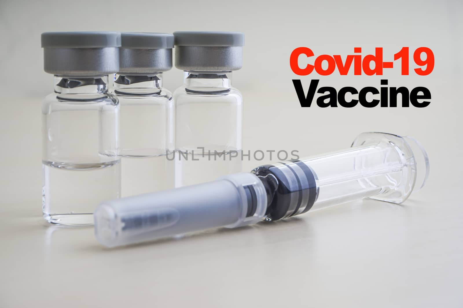 COVID -19 VACCINE text with Syringe and vials on wooden background by silverwings