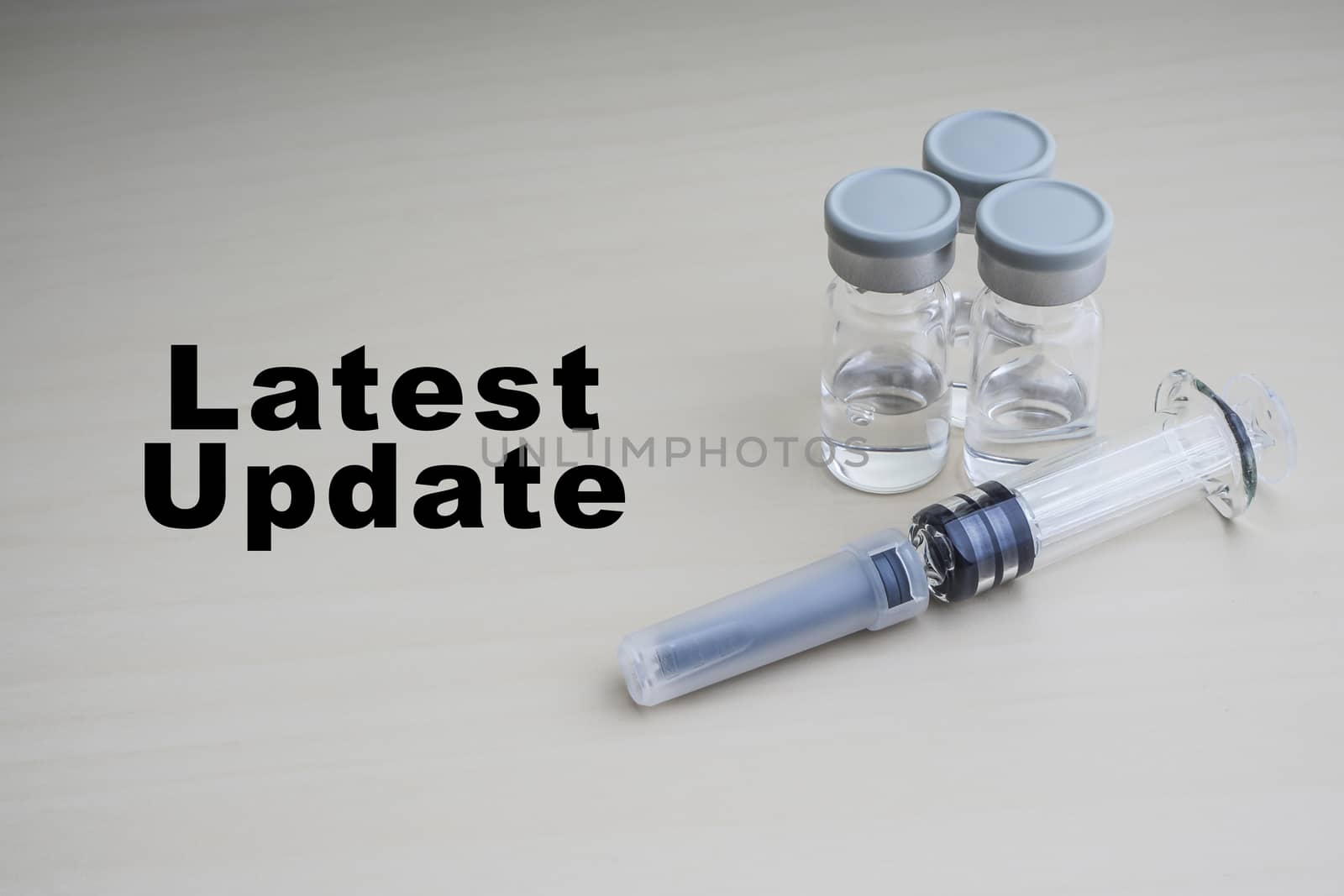 LATEST UPDATE text with Syringe and vials on wooden background  by silverwings