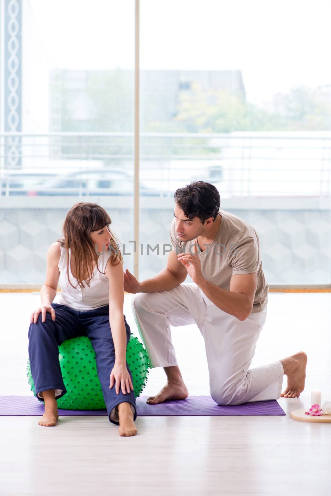 Personal coach helping woman in gym with stability ball by Elnur