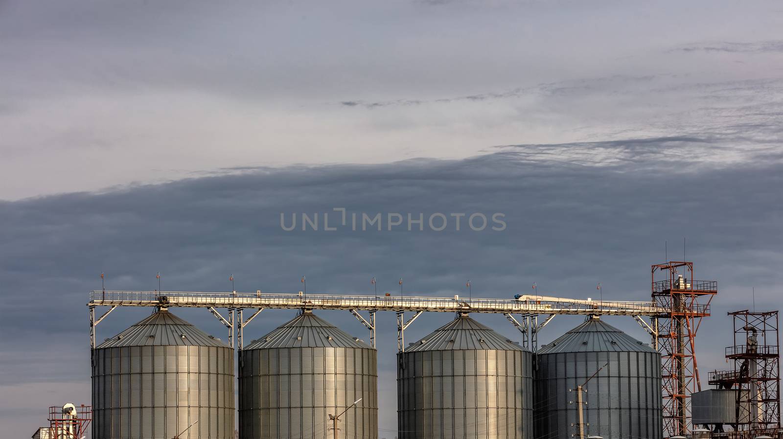 Low angle shot of grain storage units. Grey cloudy sky as a background. Altai Krai, Siberia, Russia.