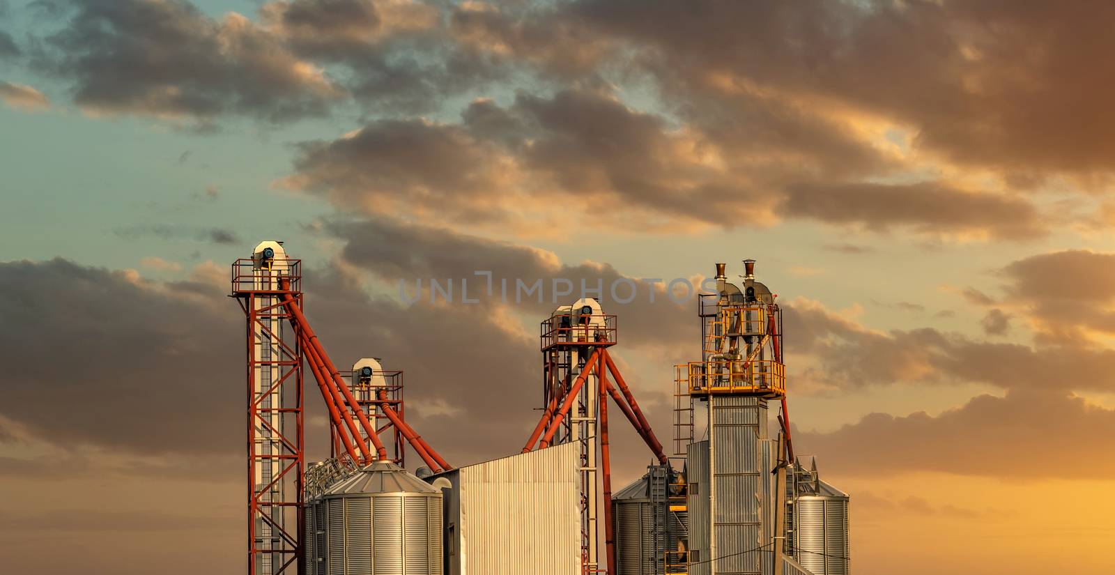 Low angle shot of a wheat processing factory. Beautiful sunset sky background. Golden hour. Altai Krai, Siberia, Russia.
