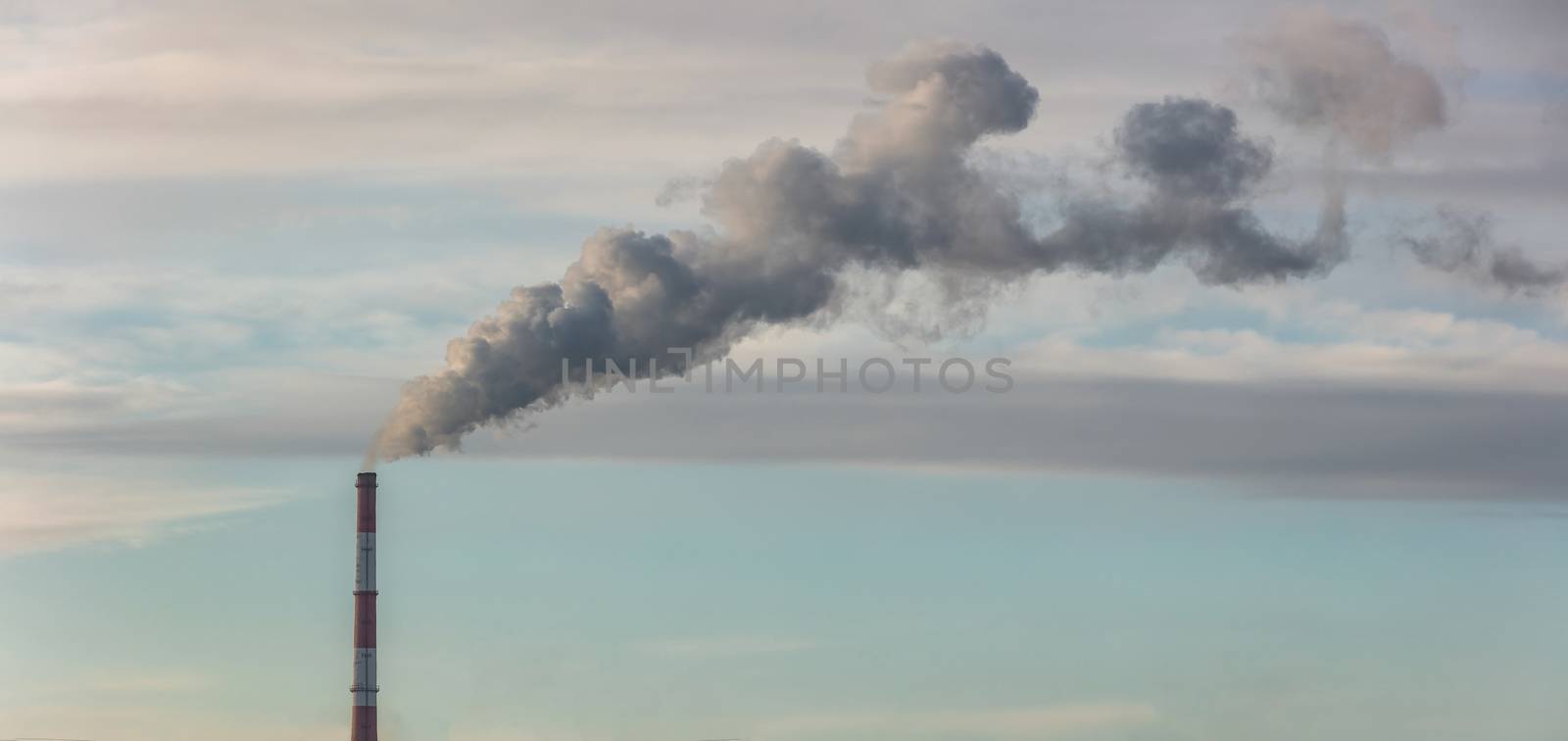 Panoramic shot of heating plant pipe that supply central heating system of the city. Smoke coming out of the pipes. Blue cloudy sky as a background. Industrial landscape. Barnaul, Russia.