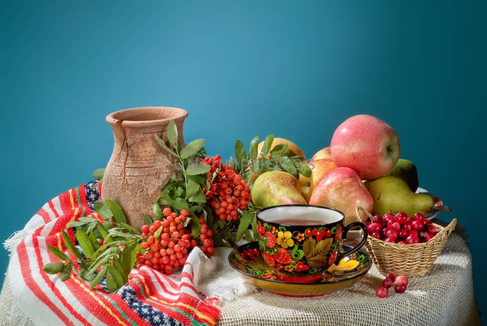 Wicker basket, ceramic vase and fruits on a studio background