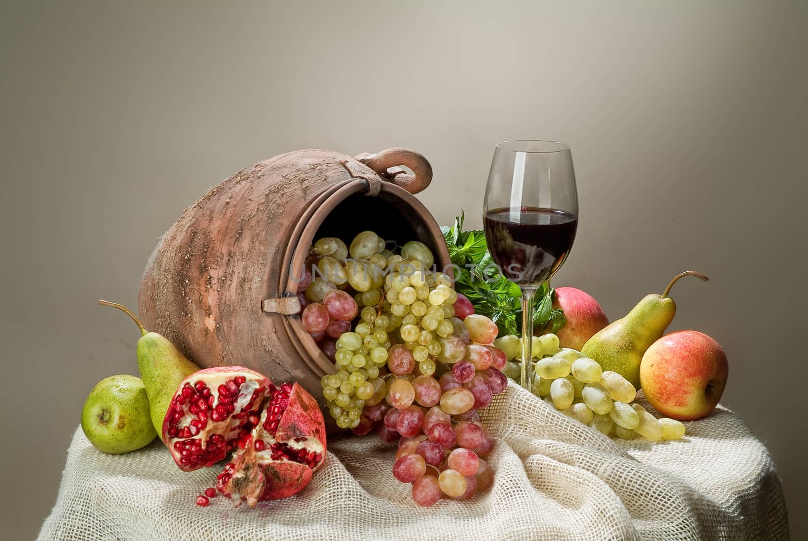 Wicker basket, ceramic vase and fruits on a studio background