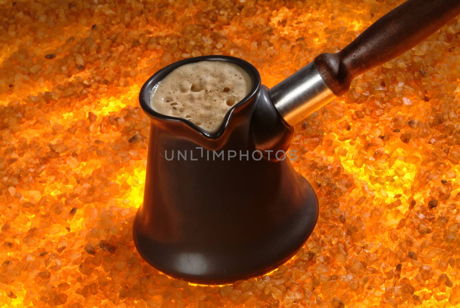 Pot with coffee on a sand background