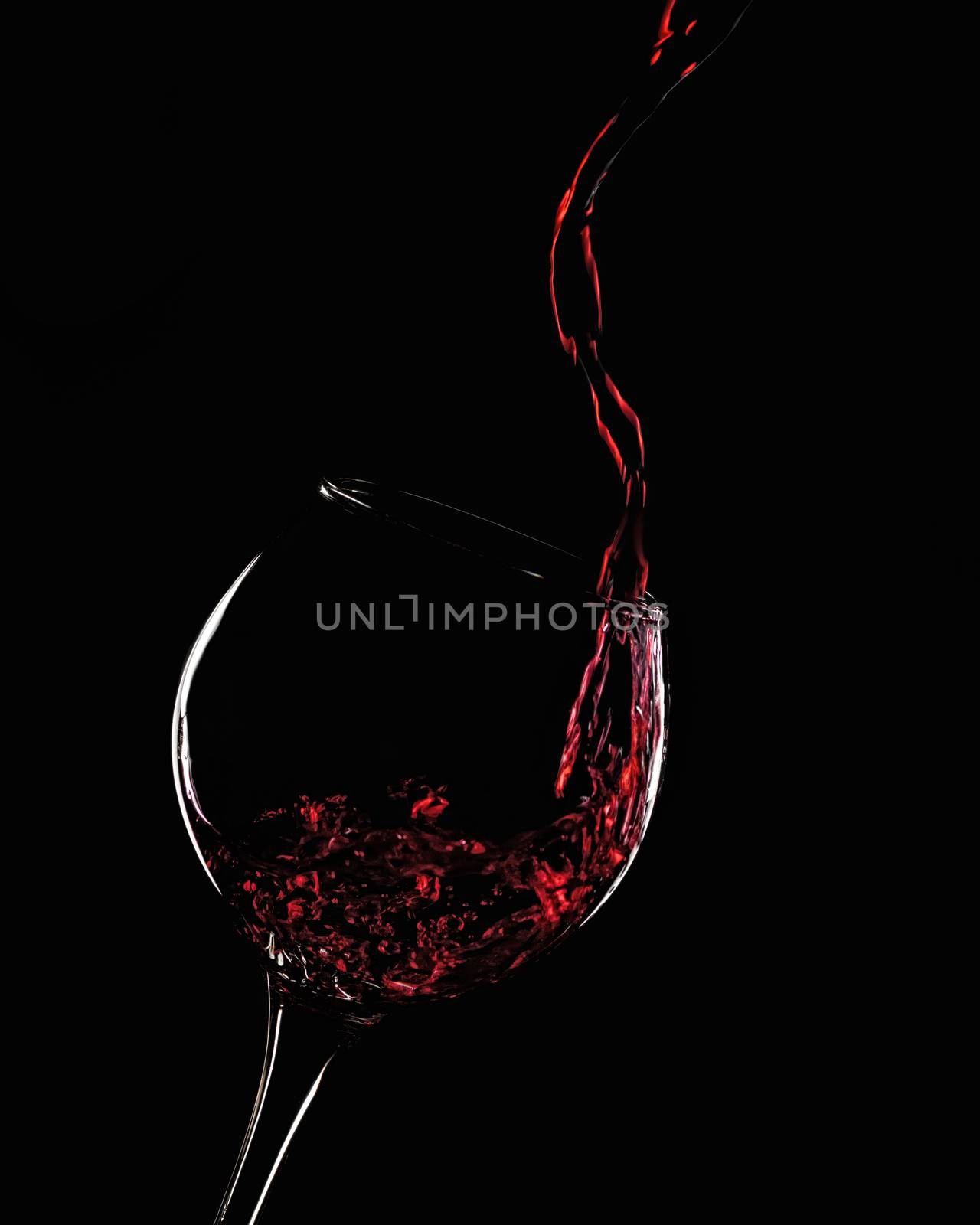 Splash of red wine in a glass on a black background close-up