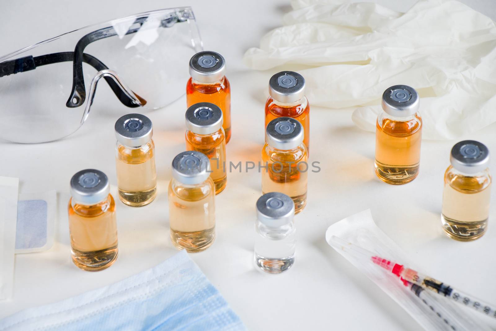 New vaccine in ampules and bottles, needle, glove and safety glass. by Taidundua