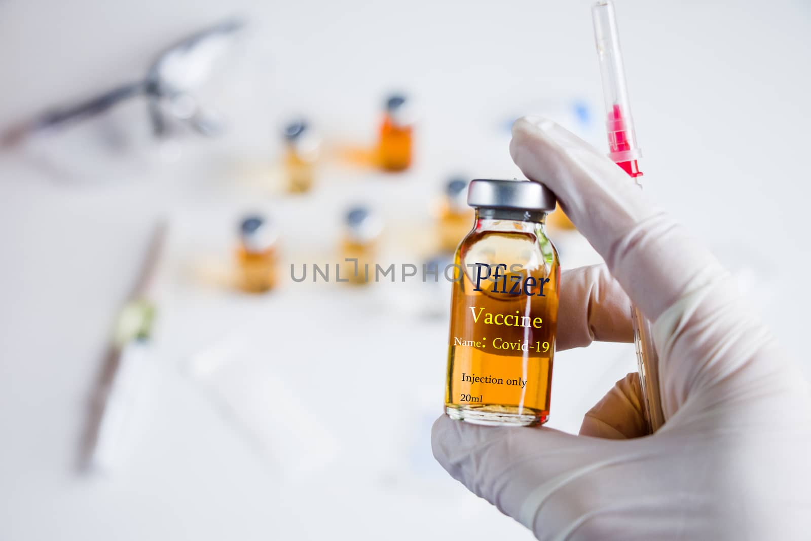Pfizer Corona virus and Covid - 19 new vaccine in ampules and bottles, needle and doctors hand. by Taidundua