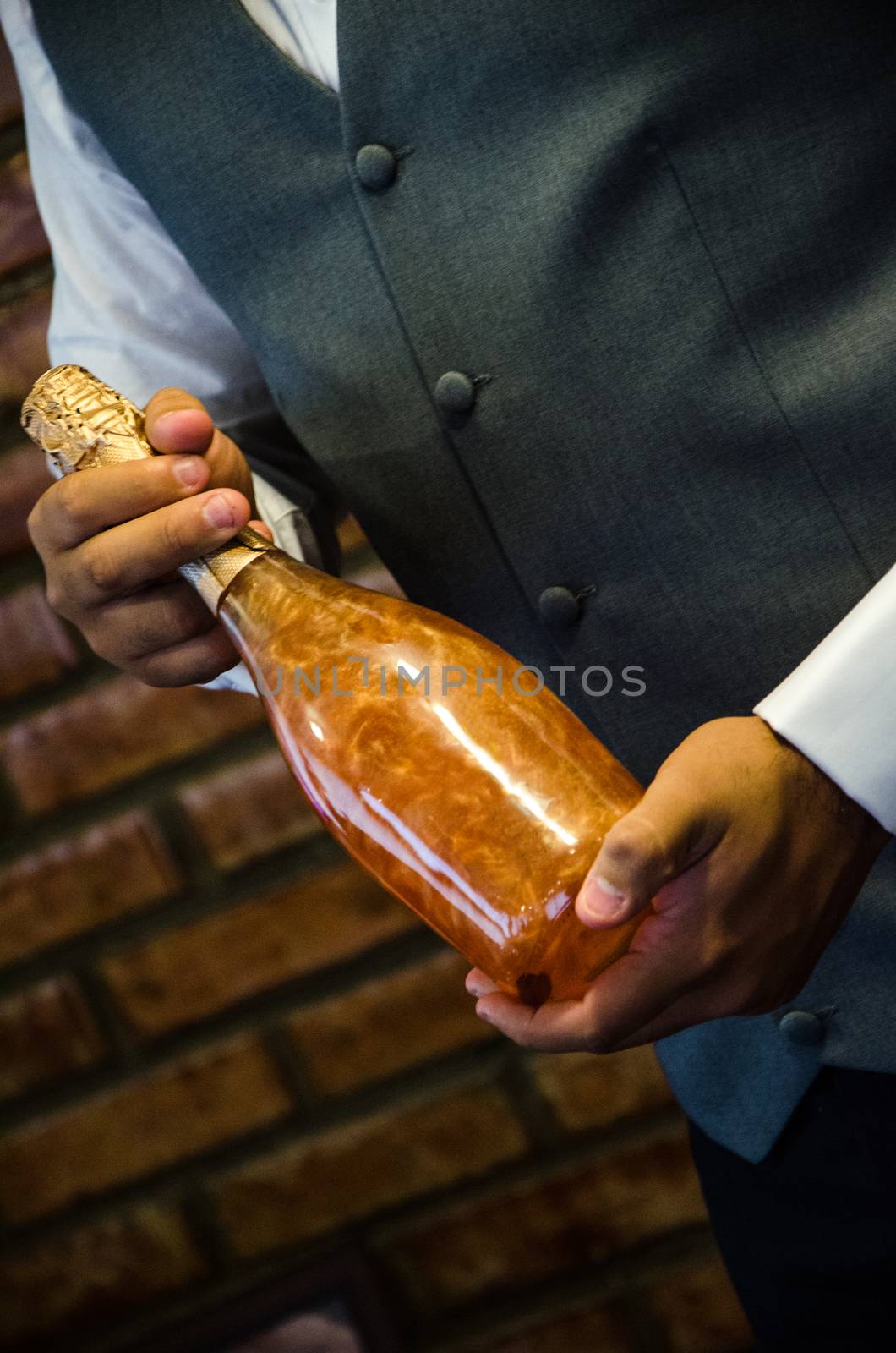 stylish man groom holding golden bottle of champagne. luxury wedding reception. catering and service at restaurant. space for text