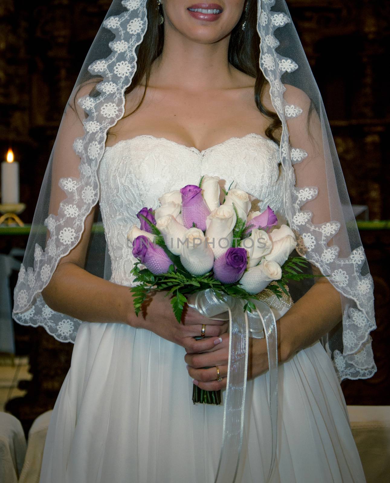 Serious young bride in veil holding bouquet in the wedding