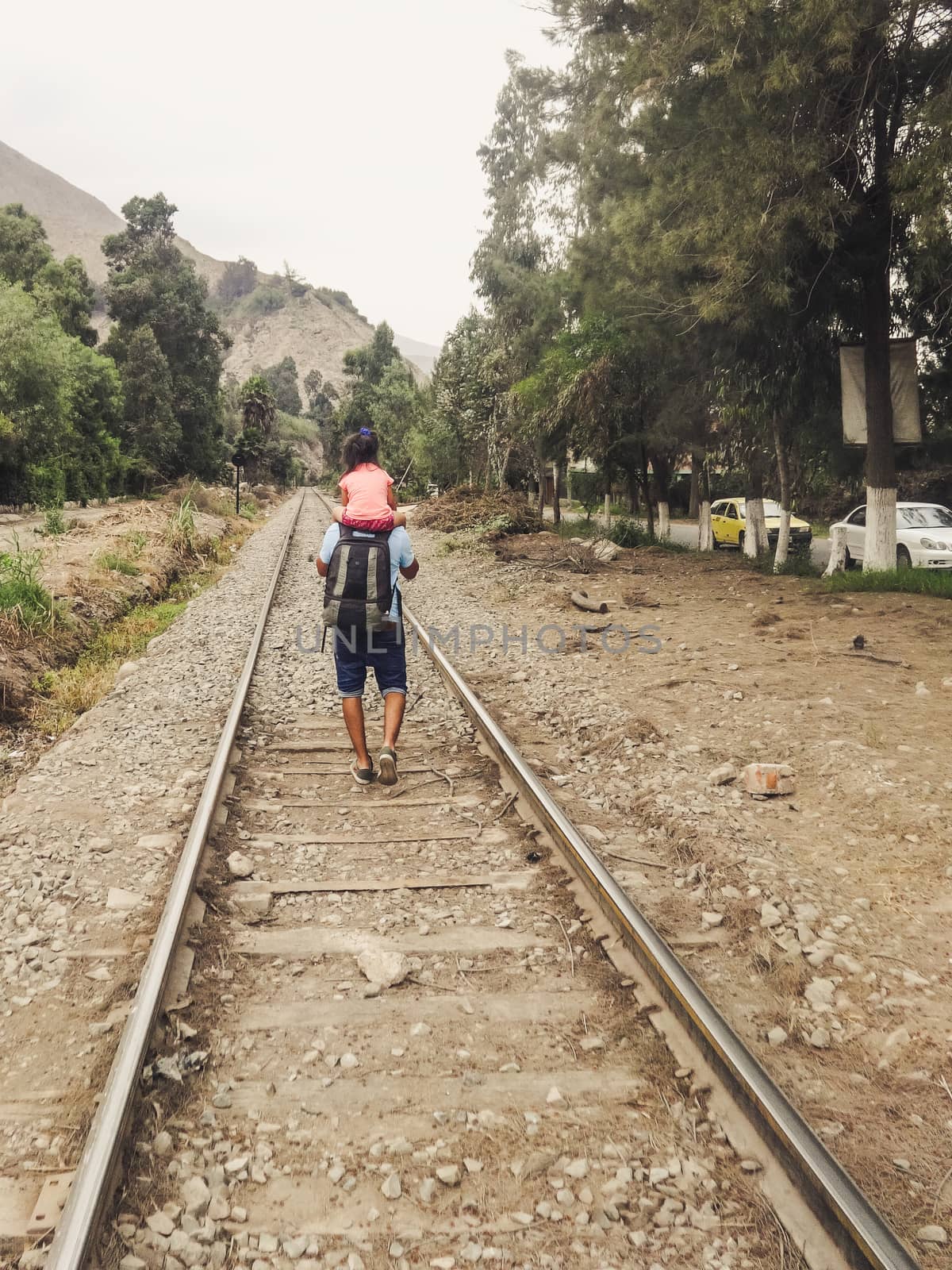 Father and daughter walking on the train tracks by Peruphotoart
