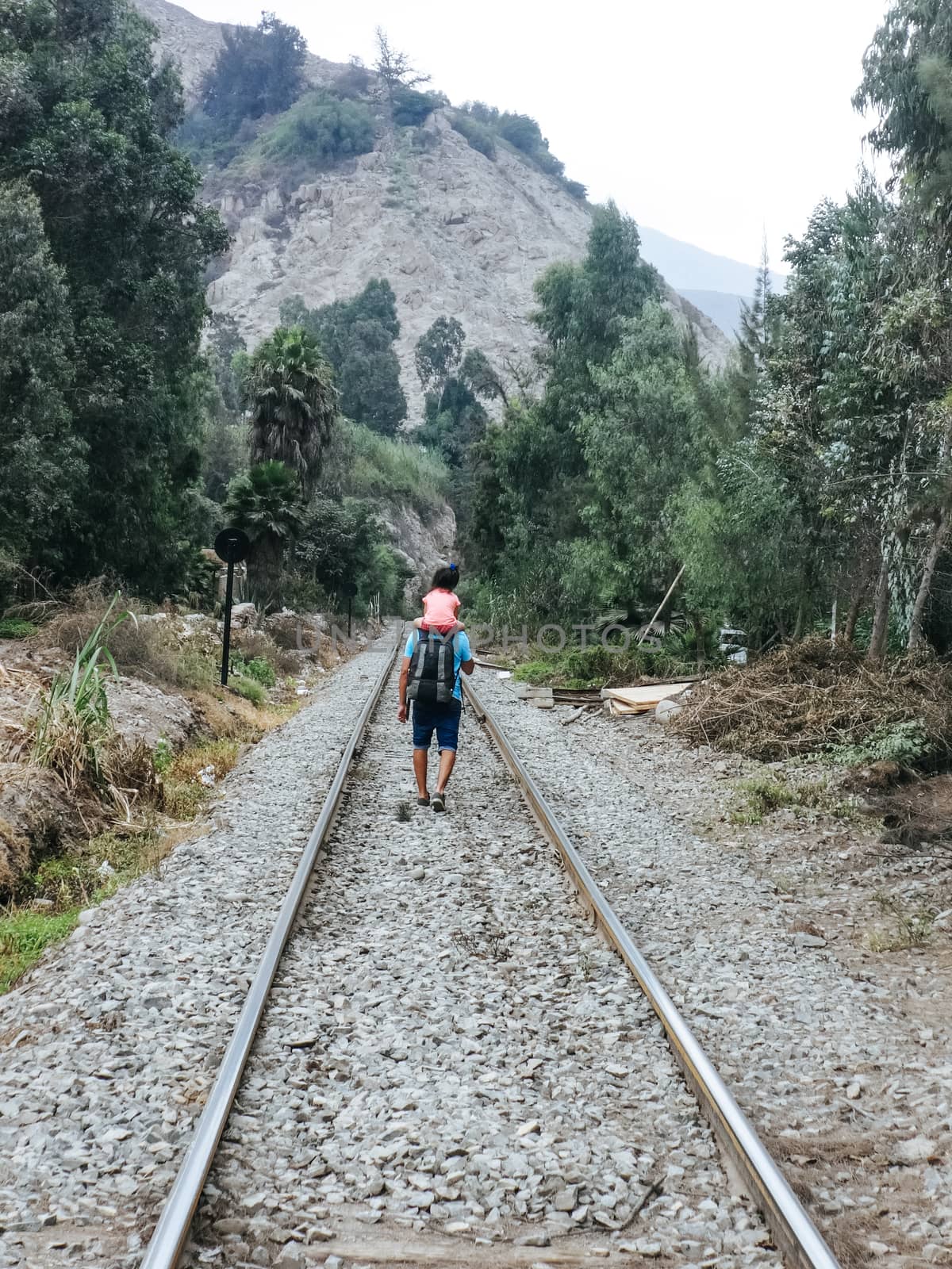 Father and daughter walking on the train tracks by Peruphotoart