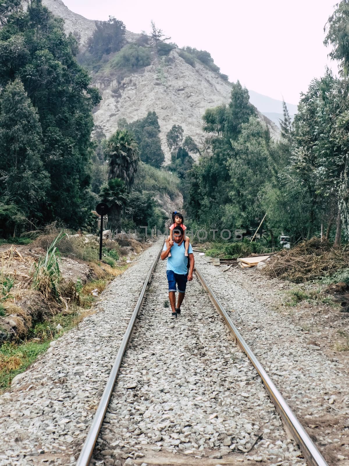 Father and daughter walking on the train tracks by Peruphotoart