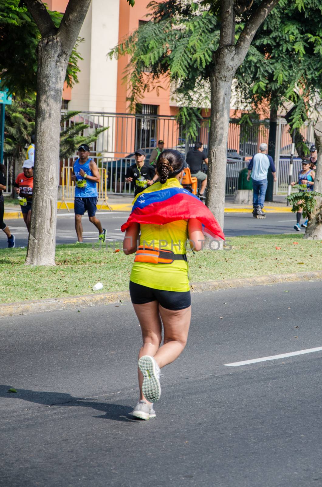 Lima, Peru - May 20th 2018: Marathon Lima 42k, sporting event that gathers athletes from all over the world. Female athlete running with the flag of Venezuela on her shoulders