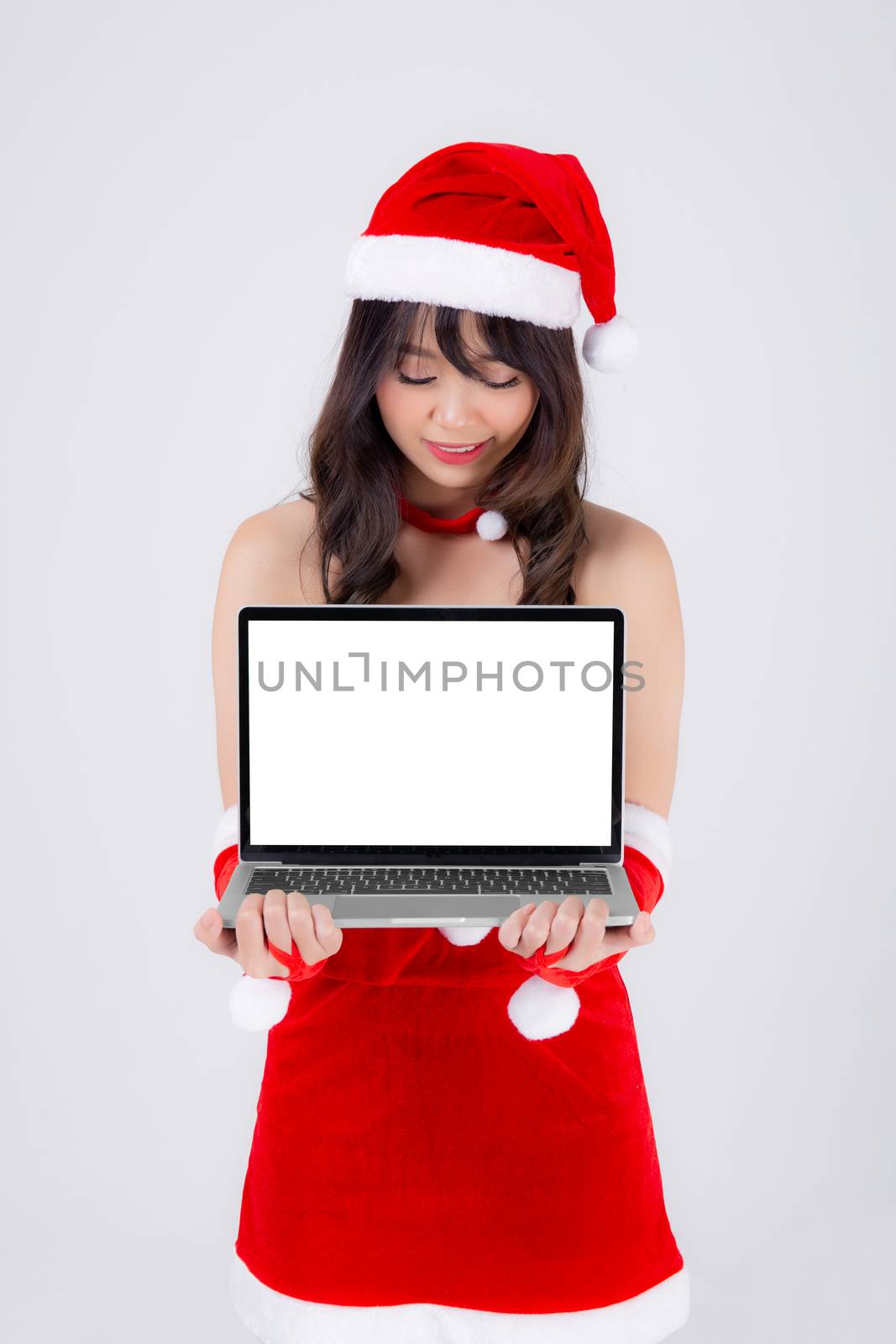 beautiful young asian woman in Santa presenting laptop computer in Christmas holiday isolated on white background, beauty asia girl holding showing notebook for celebrating in xmas day or new year.