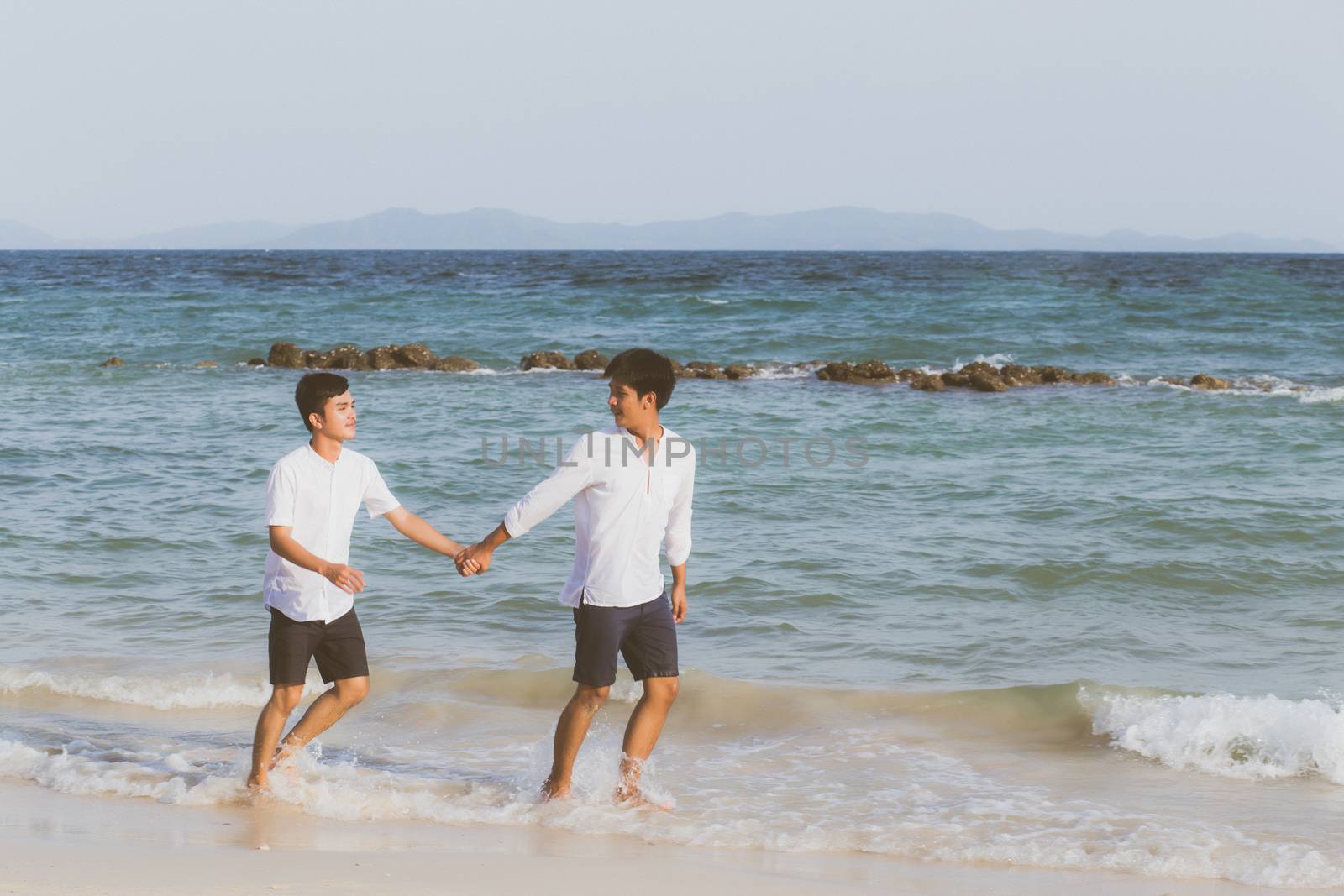 Homosexual portrait young asian couple running with cheerful together on beach in summer, asia gay going tourism for leisure and relax with happiness in vacation at sea, LGBT legal concept.