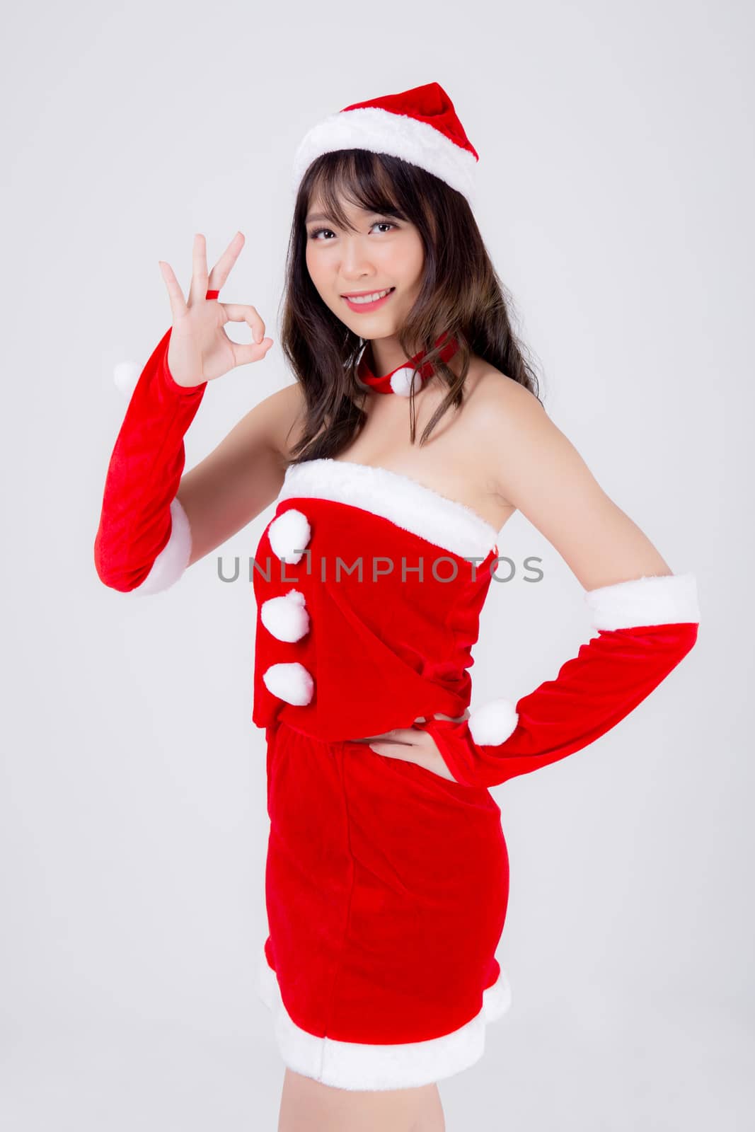 Beautiful portrait young asian woman Santa costume smiling gesture ok sign with happy in holiday xmas, beauty asia girl cheerful and happiness celebrating in Christmas isolated on white background.