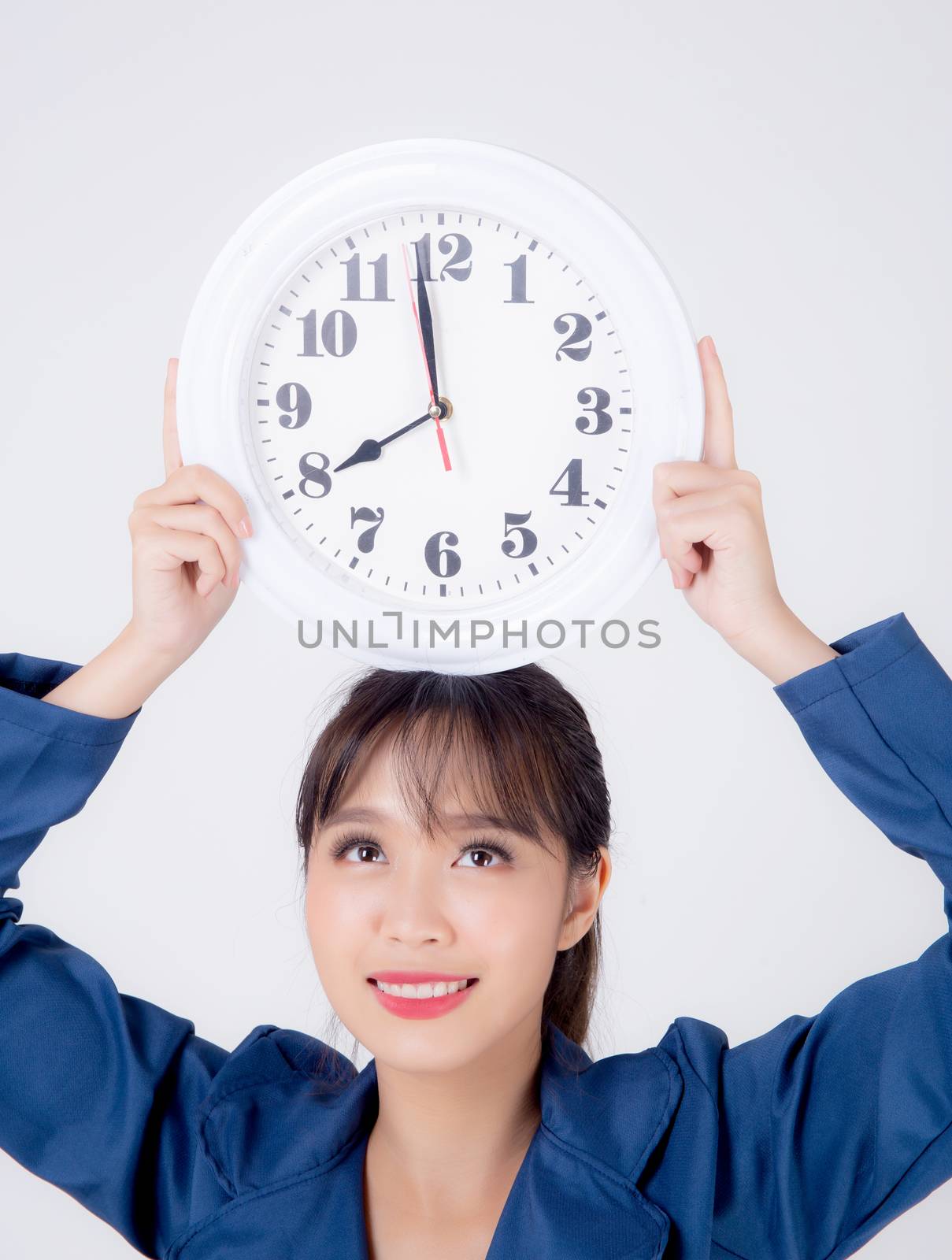 Beautiful portrait young business asian woman smiling holding clock on head isolated on white background, businesswoman schedule time of work, confident girl showing watch, management time concept.
