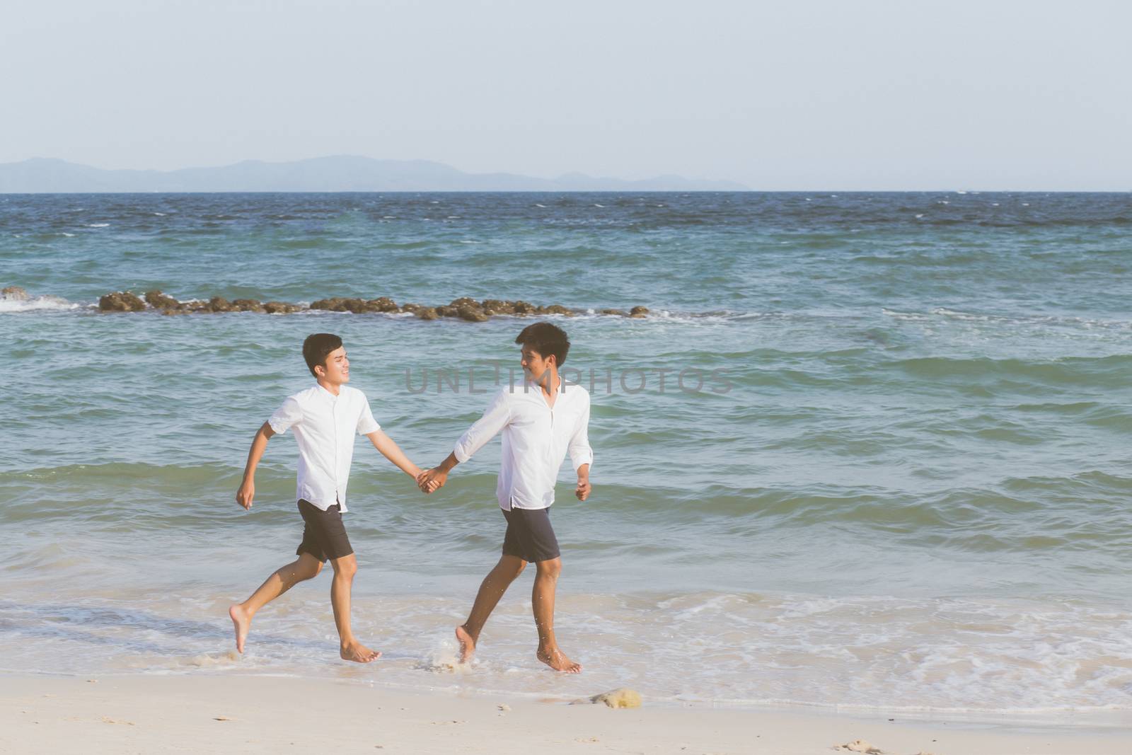 Homosexual portrait young asian couple running with cheerful together on beach in summer, asia gay going tourism for leisure and relax with happiness in vacation at sea, LGBT legal concept.