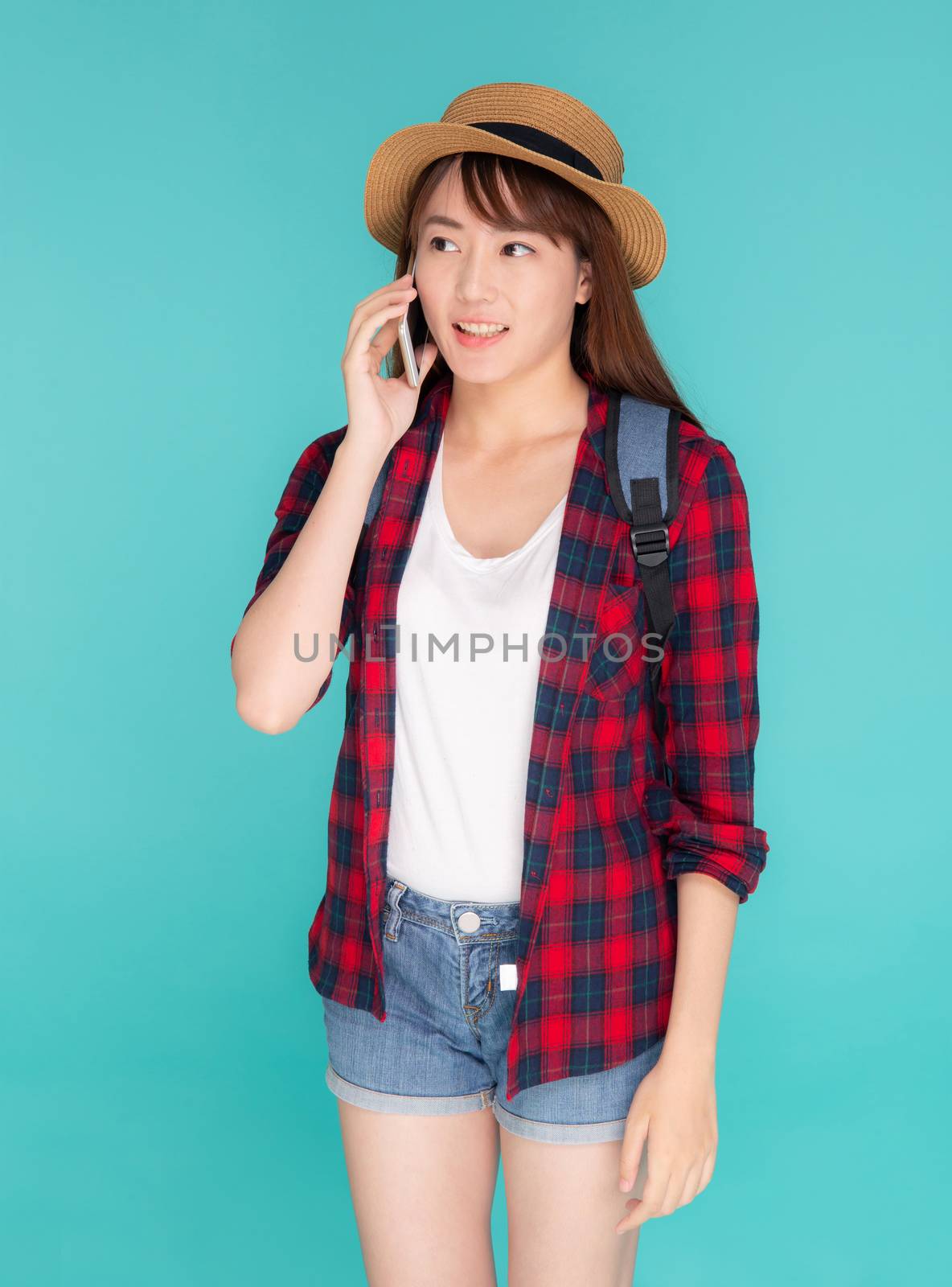 Beautiful young asian woman talking smart mobile phone in vacation isolated on blue background, asia girl conversation on smartphone in travel summer trip, journey and communication  concept.