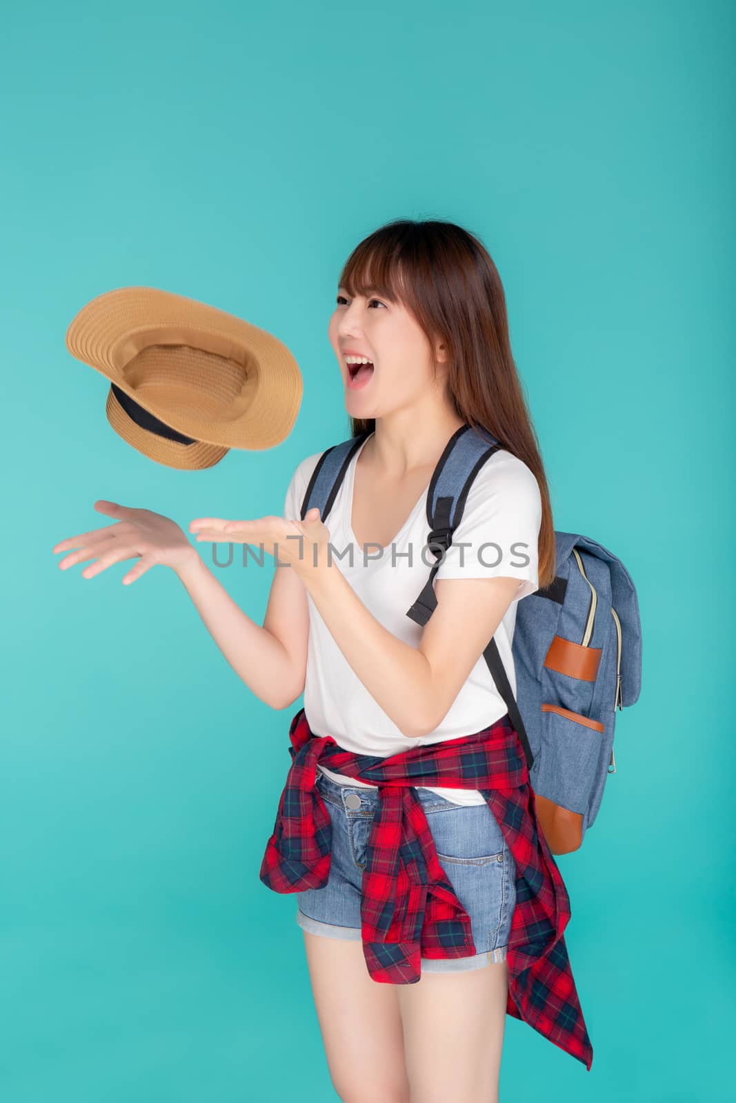 Beautiful portrait young asian woman smiling and throw hat and camera travel summer trip in vacation isolated on blue background, tourist asia girl cheerful journey with hobby in holiday concept.