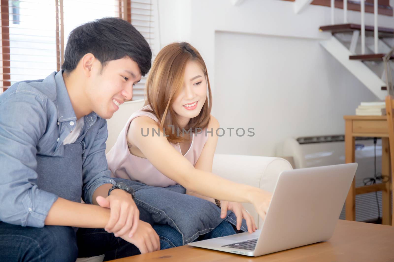 Asian young couple using laptop computer think and searching int by nnudoo