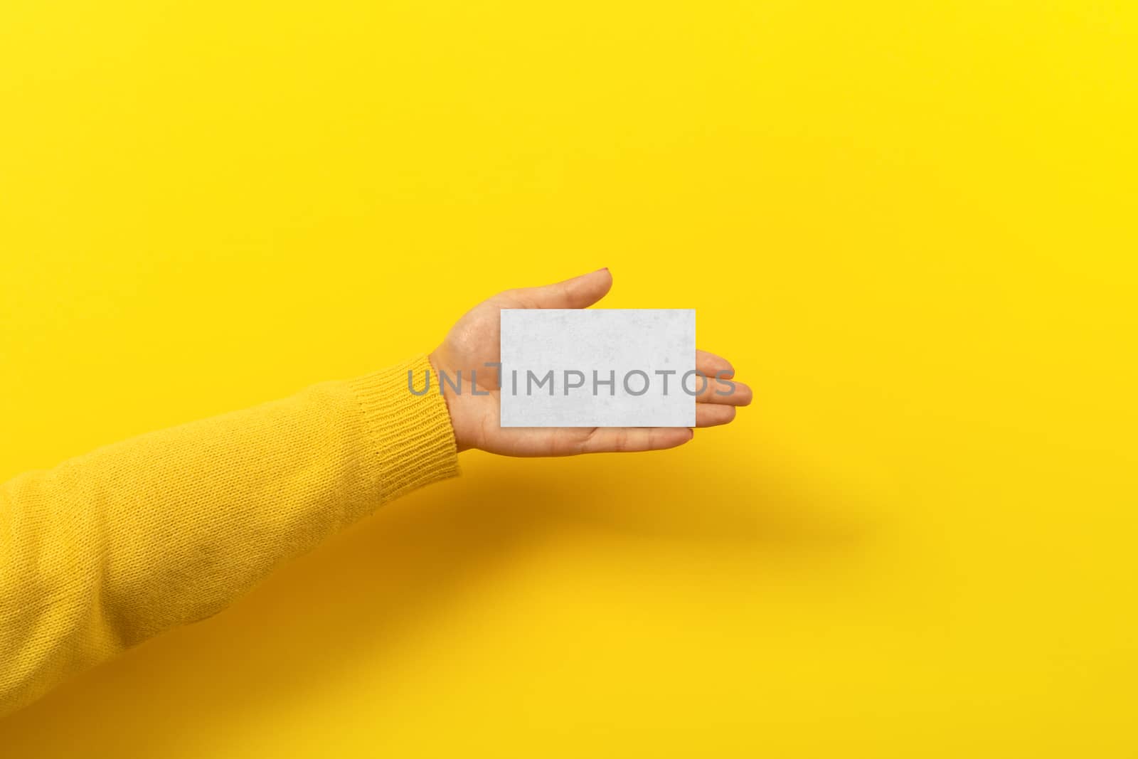 piece of paper in the female hand over yellow trendy background, empty blank for advertisement