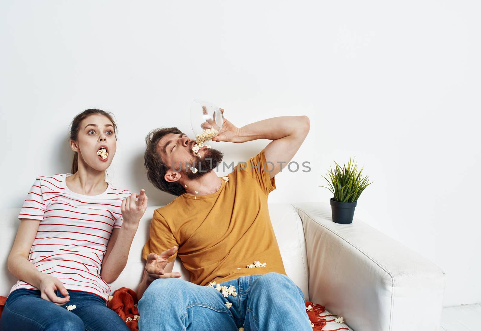 Man and woman watching movies indoors with popcorn and flower in a pot. High quality photo