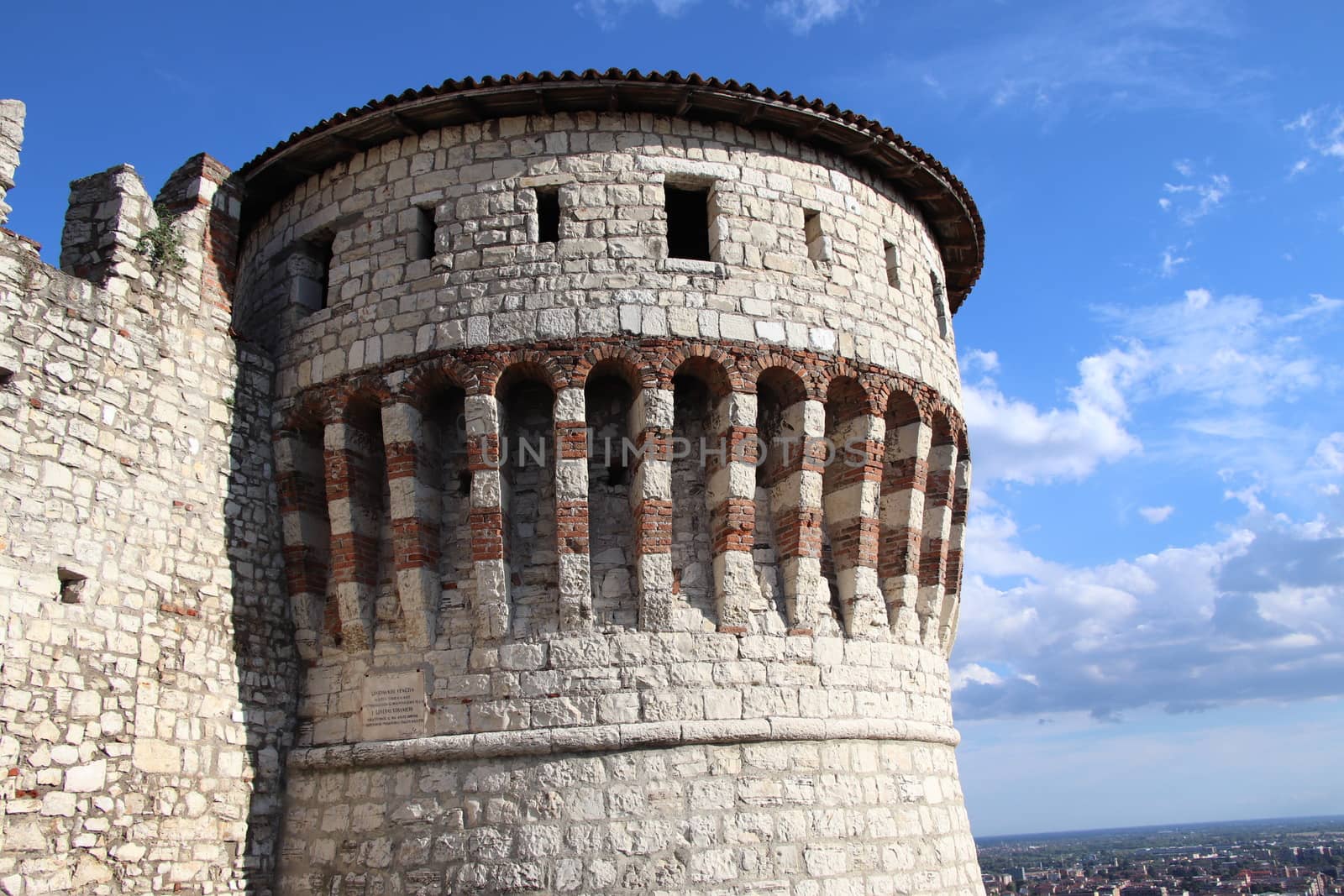 Stone wall with merlons and drawbridge gate of medieval castle of Brescia in north Italy