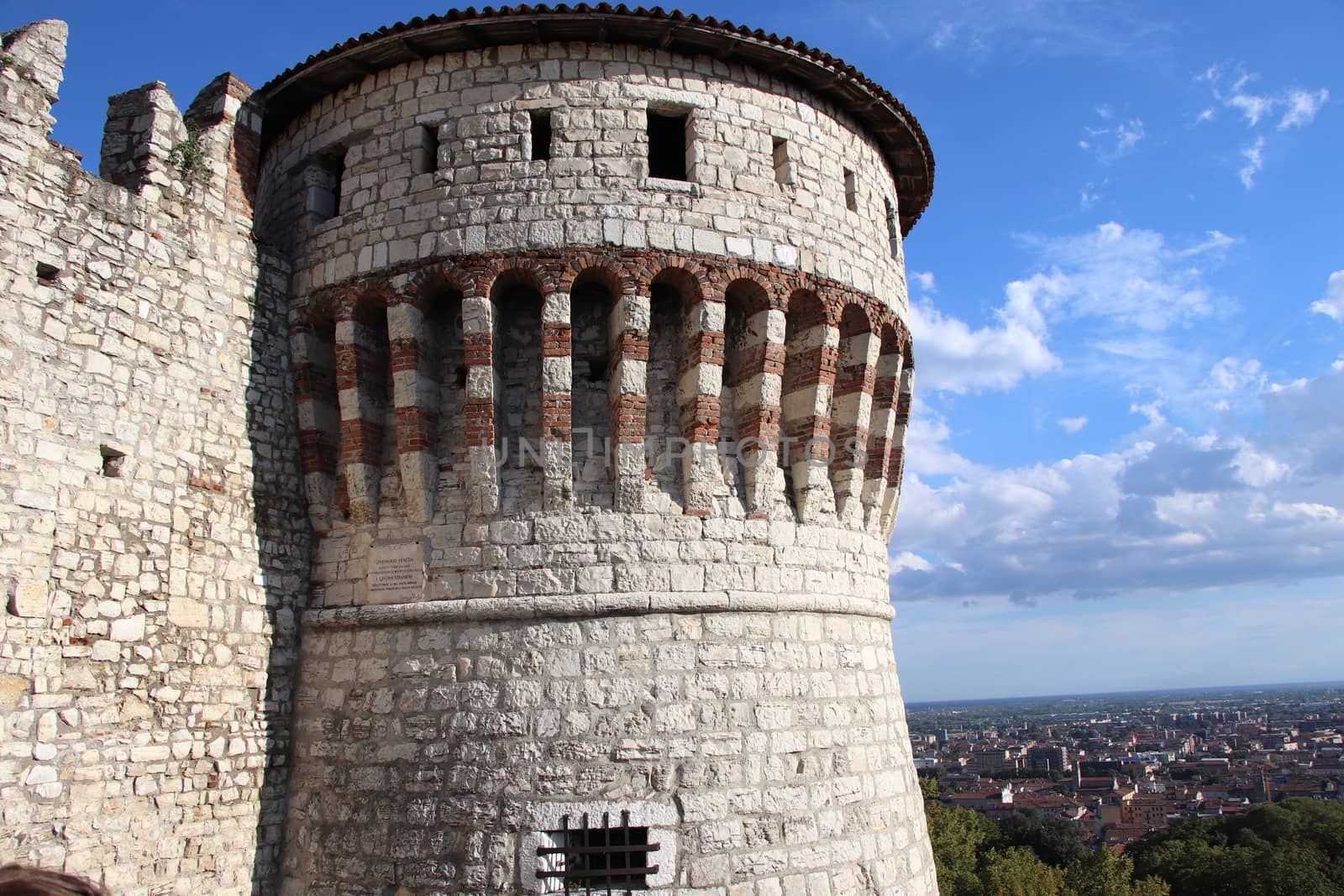 Stone wall with merlons and drawbridge gate of medieval castle of Brescia in north Italy