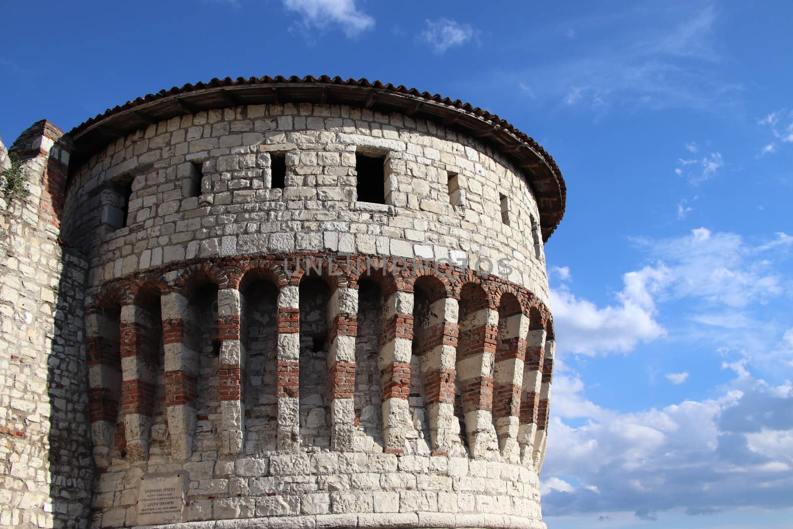 Stone wall with merlons and drawbridge gate of medieval castle of Brescia in north Italy