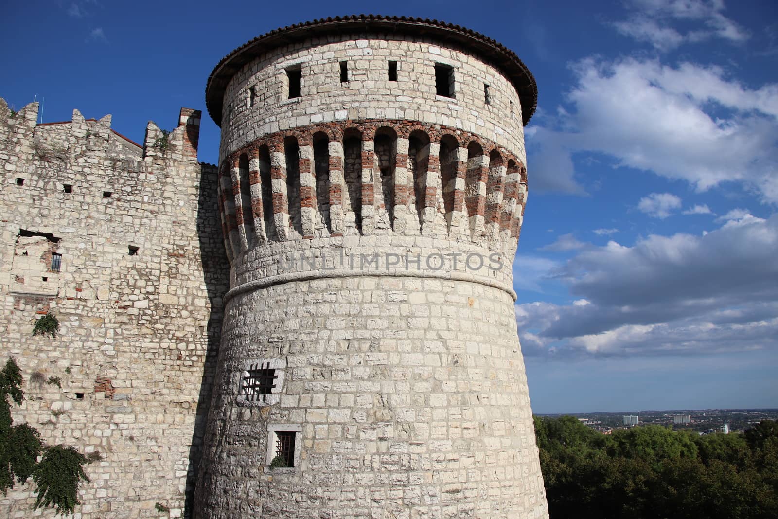 Stone wall with merlons and drawbridge gate of medieval castle of Brescia in north Italy