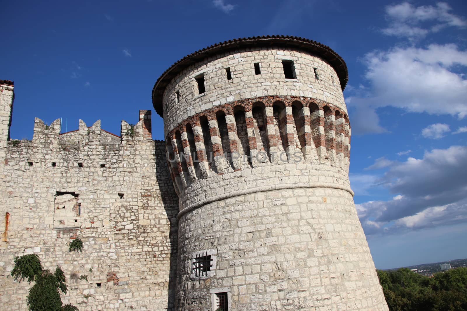 Stone wall with merlons and drawbridge gate of medieval castle of Brescia in north Italy