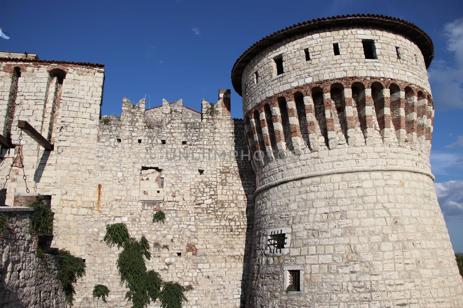 Stone wall with merlons and drawbridge gate of medieval castle of Brescia in north Italy